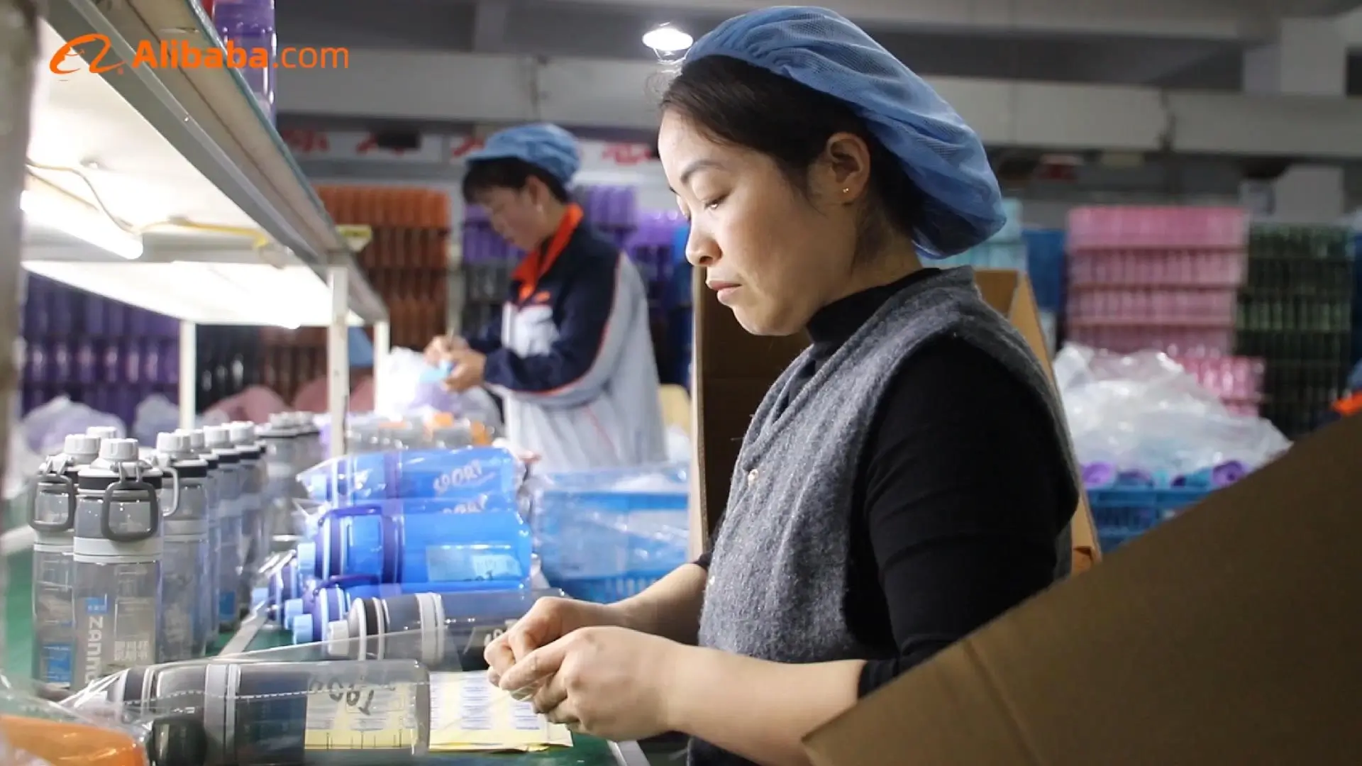Worker in hairnet packing water bottles on Seliya production line